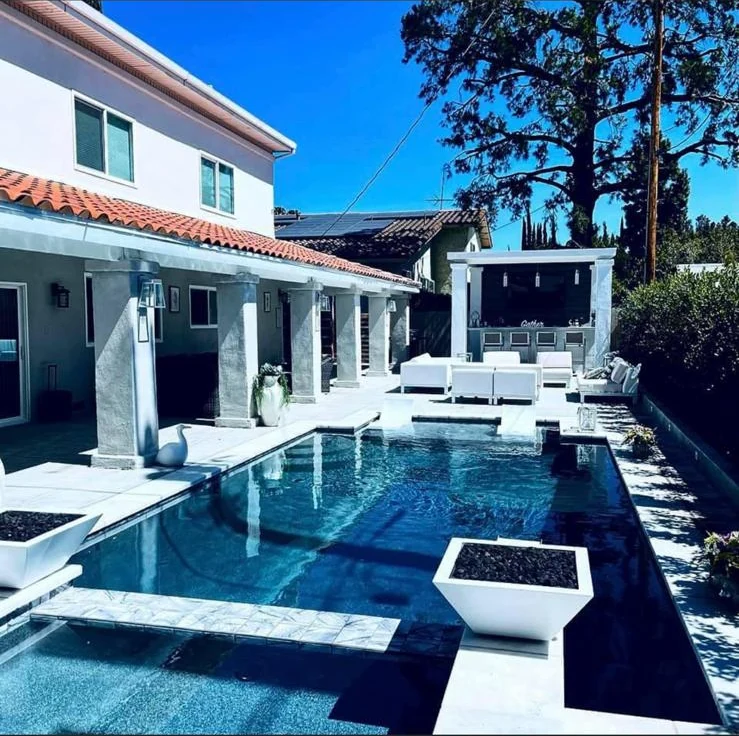Completed Encino backyard remodel with a modern pool, spa, covered patio, and outdoor kitchen