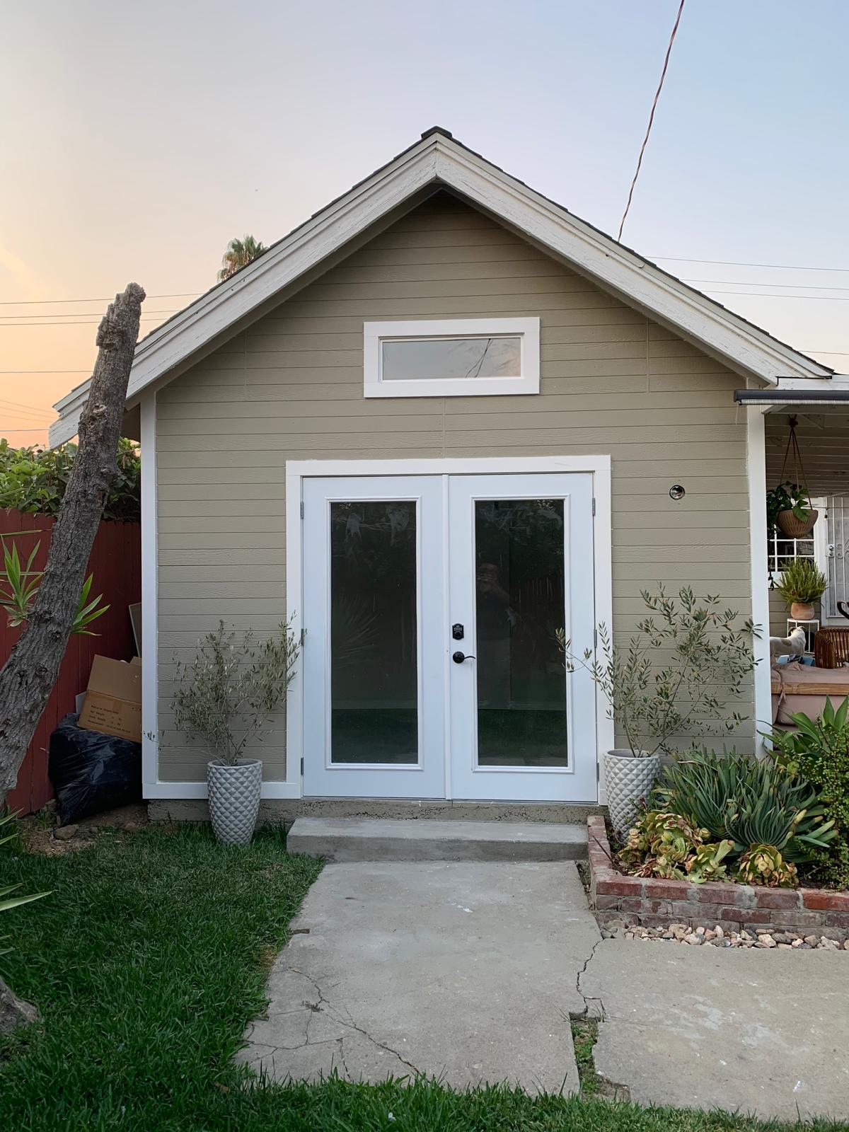 Completed detached North Hollywood ADU with gabled roof, horizontal siding, white trim, and French doors