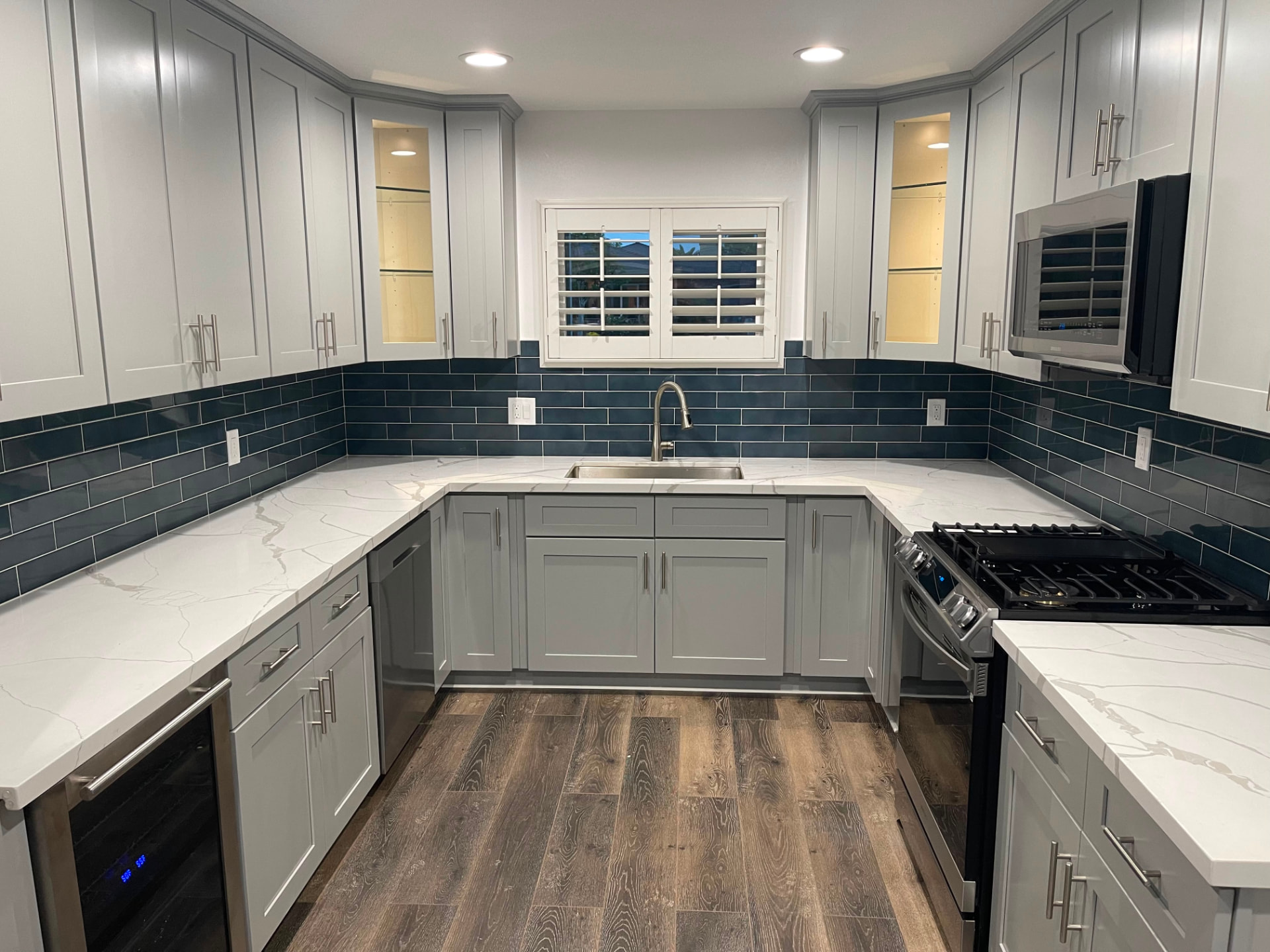 Completed Glendora kitchen remodel with gray shaker cabinets, white counters, and a navy subway tile backsplash